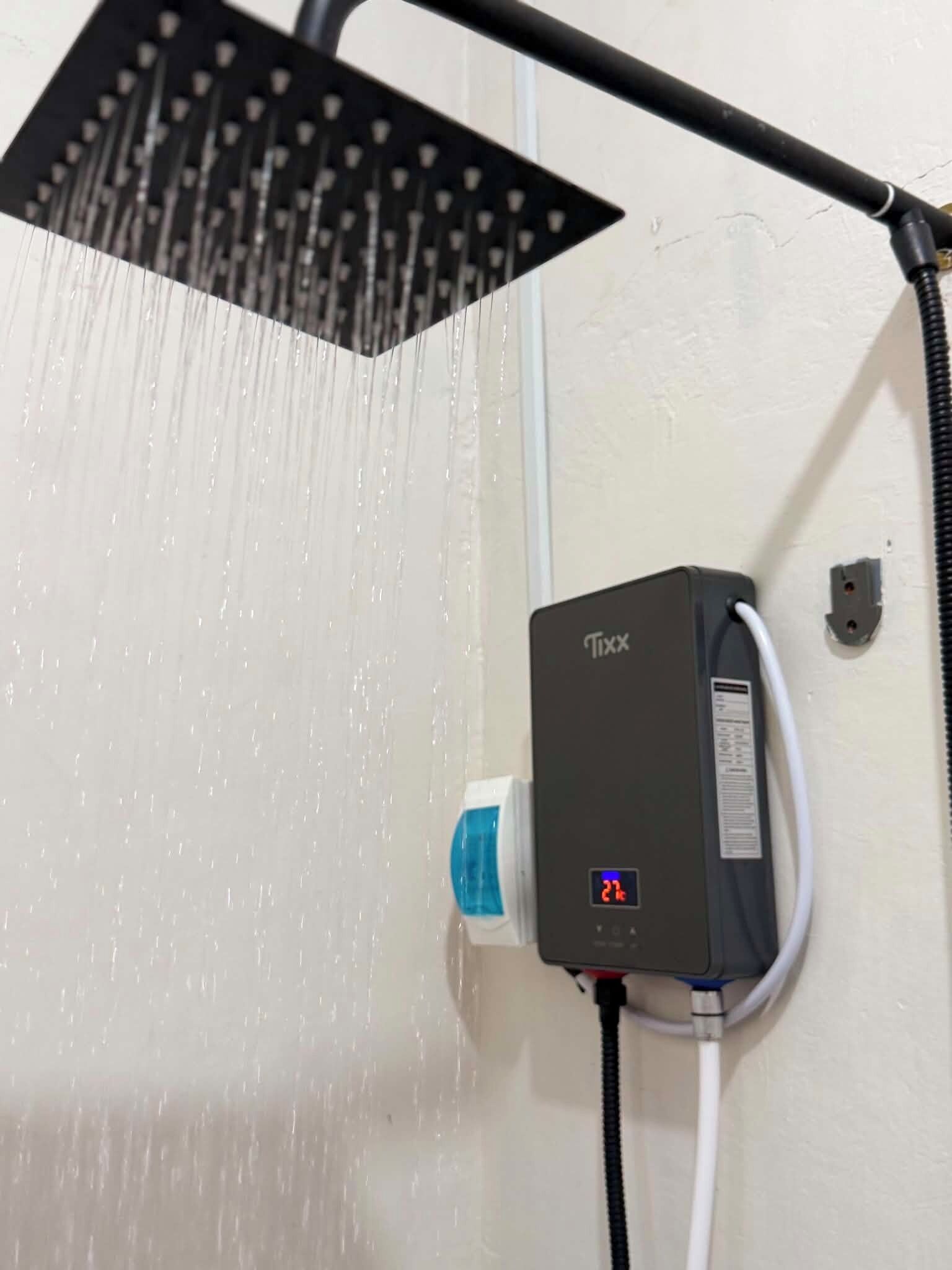 Eine Dusche mit digitaler Anzeige, einer Handbrause und einer an der Wand montierten Bedieneinheit.