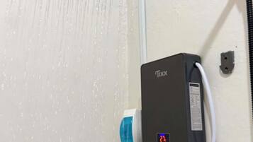 Eine Dusche mit digitaler Anzeige, einer Handbrause und einer an der Wand montierten Bedieneinheit.