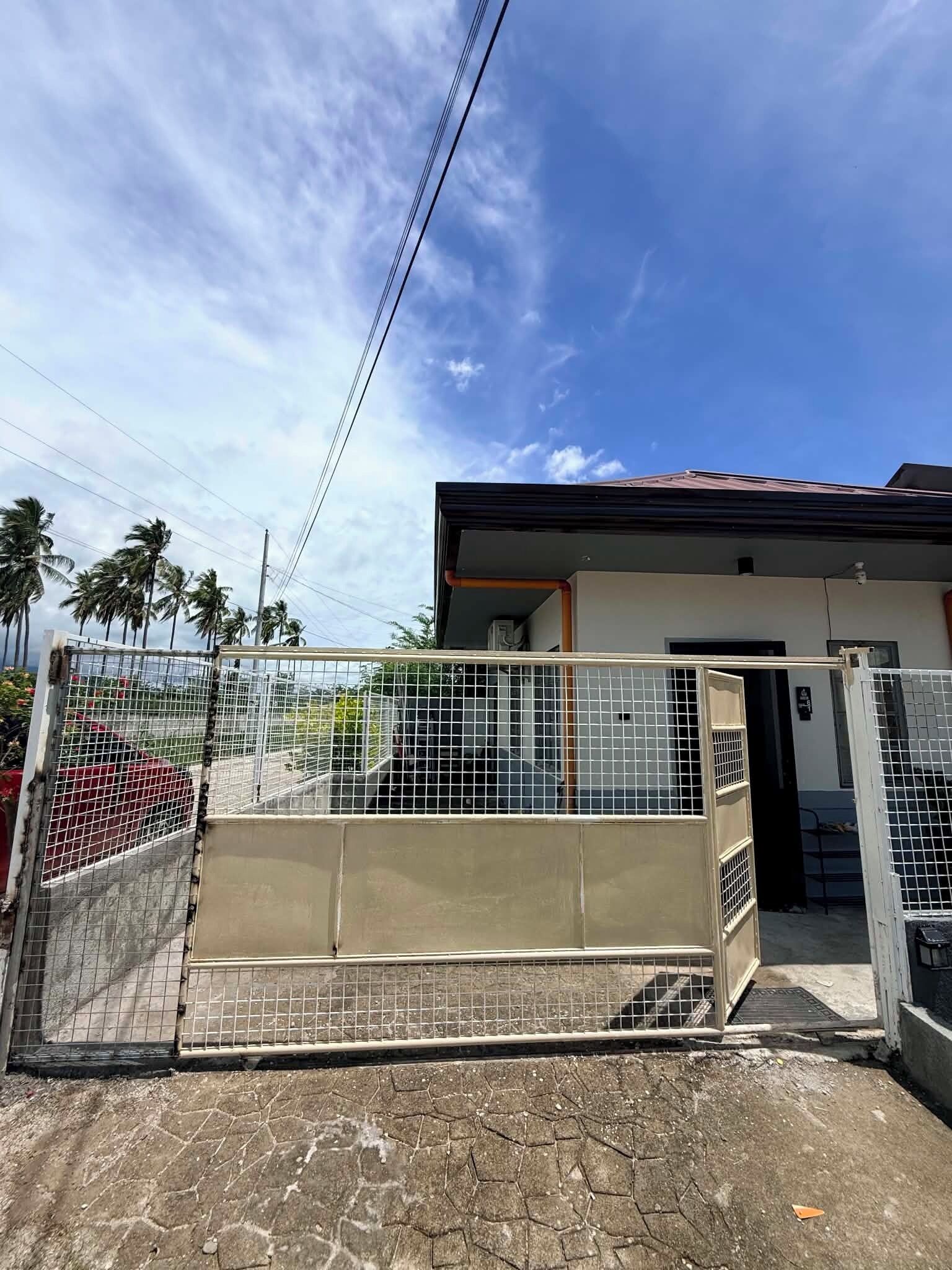 A gated property with a metal fence, a concrete entrance, and a building with a red roof.