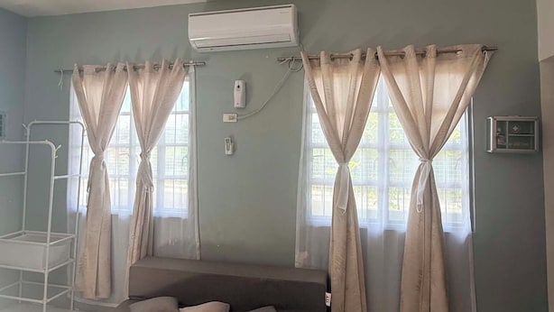 Une chambre avec un lit, des rideaux, un appareil de climatisation et une fenêtre.