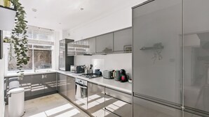 Una cocina moderna con un ventanal grande, electrodomésticos de acero inoxidable y encimera blanca.