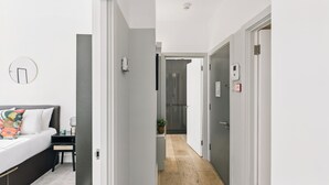 Una habitación de hotel moderna con cama, mesita de noche y vistas al pasillo.