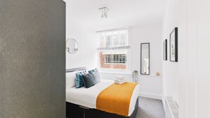 Un dormitorio moderno con cama, ventana y radiador.