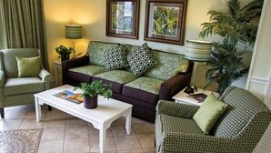 A living room with a sofa, two armchairs, a coffee table, and a lamp.