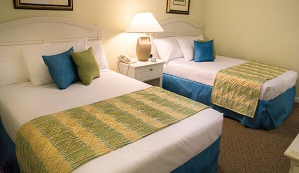 A hotel room with two beds, each with a blue bedspread and a green and yellow striped blanket. There is a nightstand with a lamp and a phone between the beds. - Wyndham Grand Palms, 2-bedroom condo with WiFi, AC in marvelous Surfside Beach (Surfside Beach)