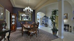 A dining area with a chandelier, a large mirror, and a patterned floor.
