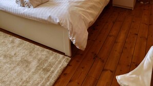 A neatly made bed with white linens and towels, a wooden floor, and bedside lamps on nightstands. - Stylish Happiness Home in Surrey (Oxted)