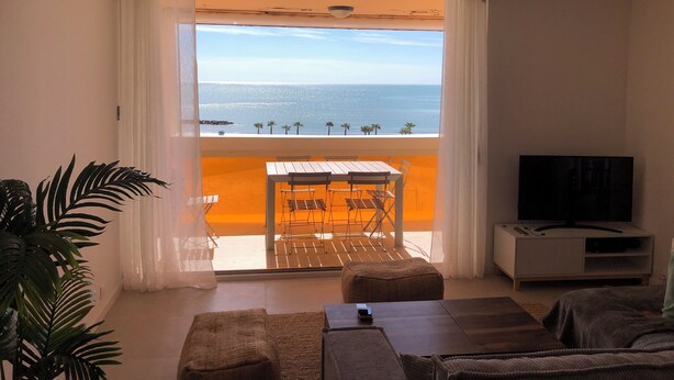 A room with a balcony, a TV, and a dining area with a table and chairs.