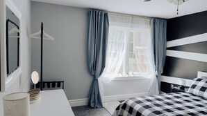 Una camera da letto con un letto, un comodino, uno specchio, un termosifone e una finestra con tende.