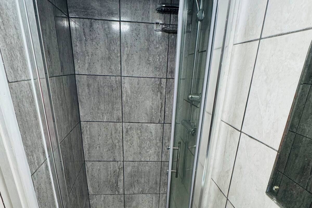 Ein Badezimmer mit Dusche, Waschbecken und Spiegel.