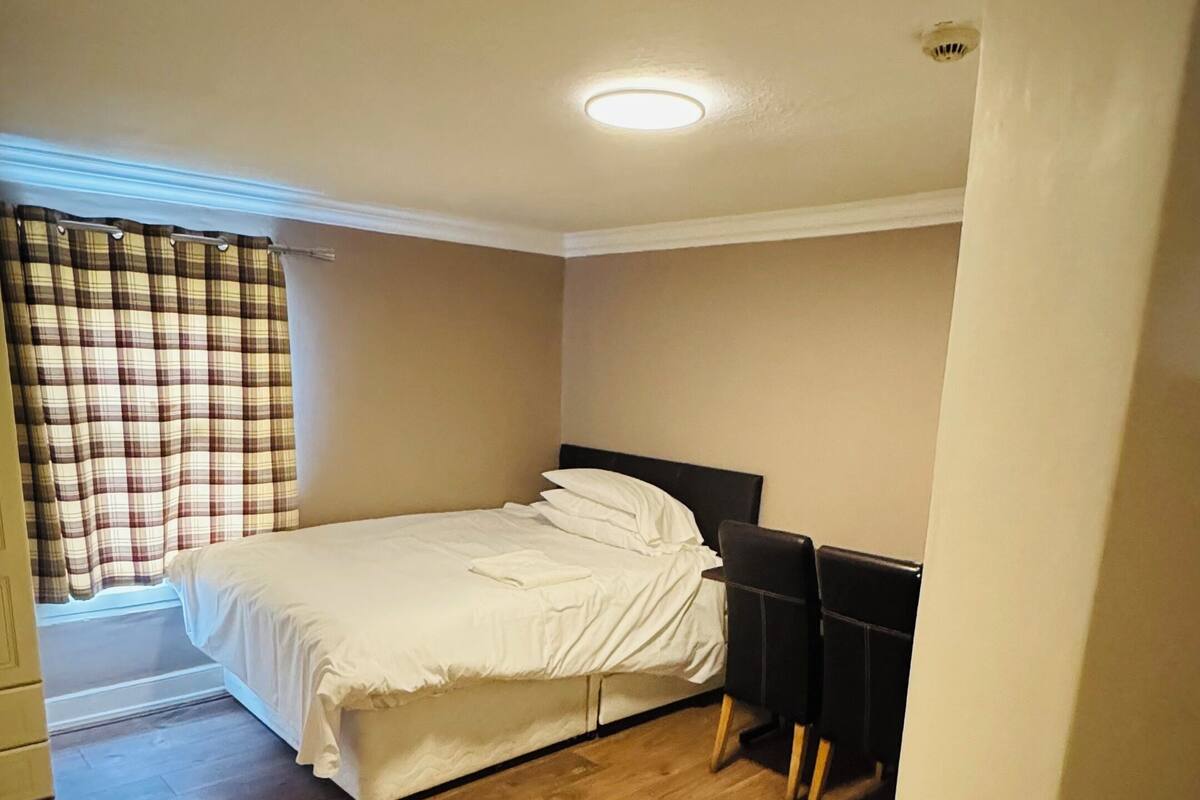 Ein Schlafzimmer mit einem Bett, einem Schreibtisch und einem fenster mit Vorhängen.