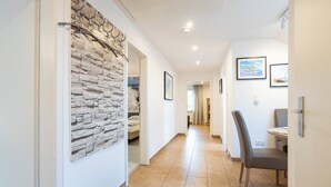 Un couloir avec un mur en pierre, une porte dotée d’une poignée en métal et un coin repas comprenant une chaise et une table.