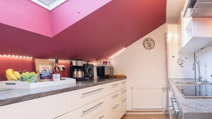 Une cuisine moderne avec des meubles blancs, un plan de travail noir et un plafond rouge.