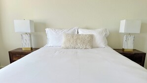 A neatly made bed with white linens and two nightstands with lamps. - Homestead Village - Two Bedroom Condo Top Floor (Sandpoint)