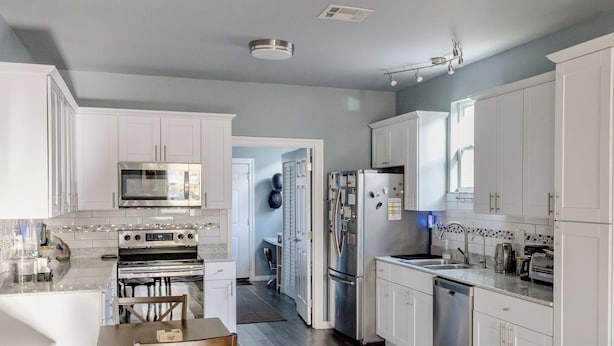 Una cocina moderna con armarios blancos, electrodomésticos de acero inoxidable y una mesa de comedor de madera.