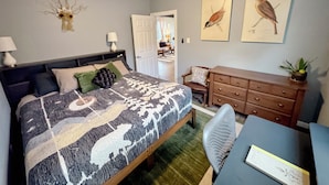 Un dormitorio con cama, escritorio, silla, cómoda y ventilador de techo.