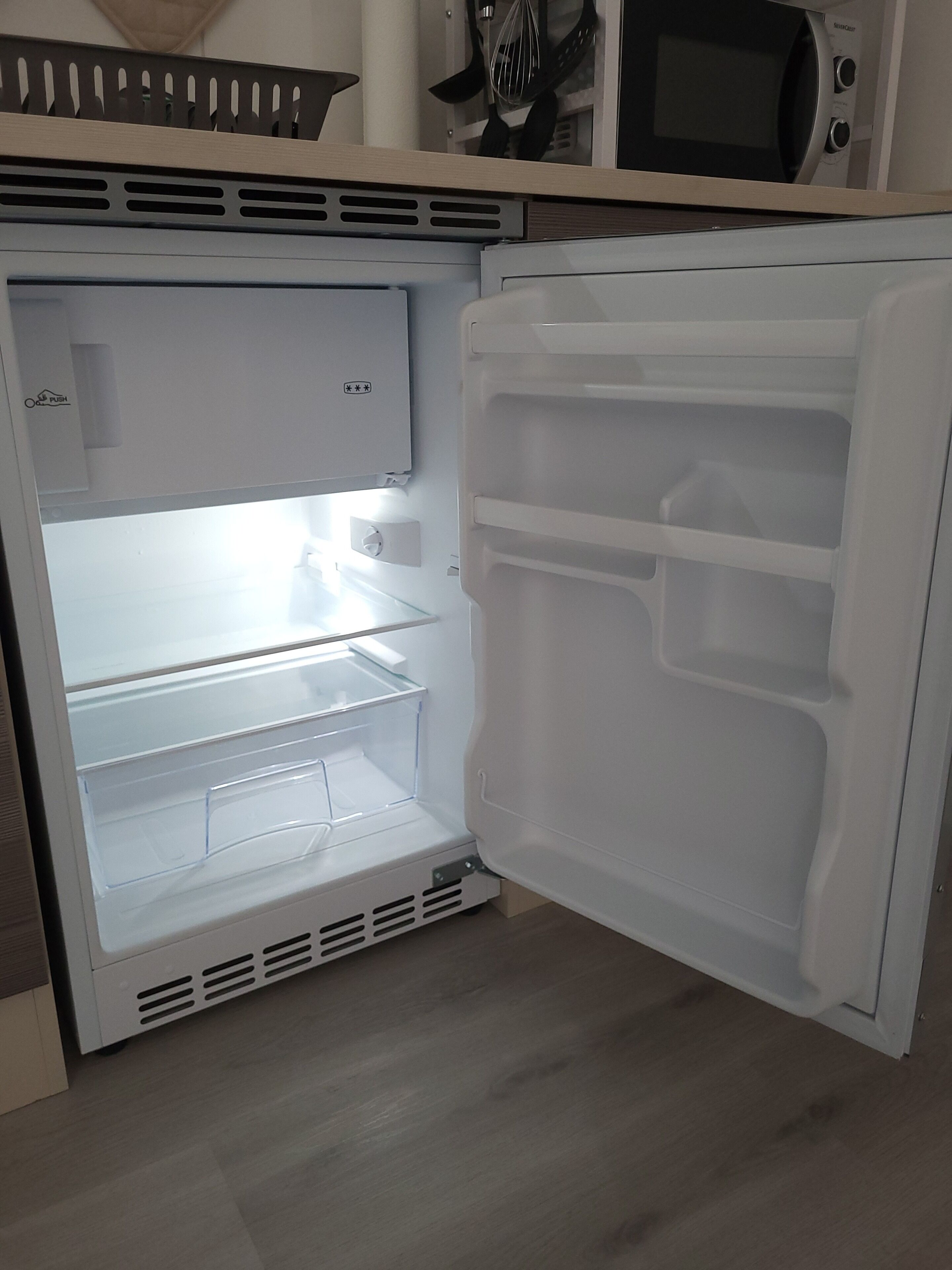 Ein offener Kühlschrank mit mehreren Ablagen und einem Gefrierfach.