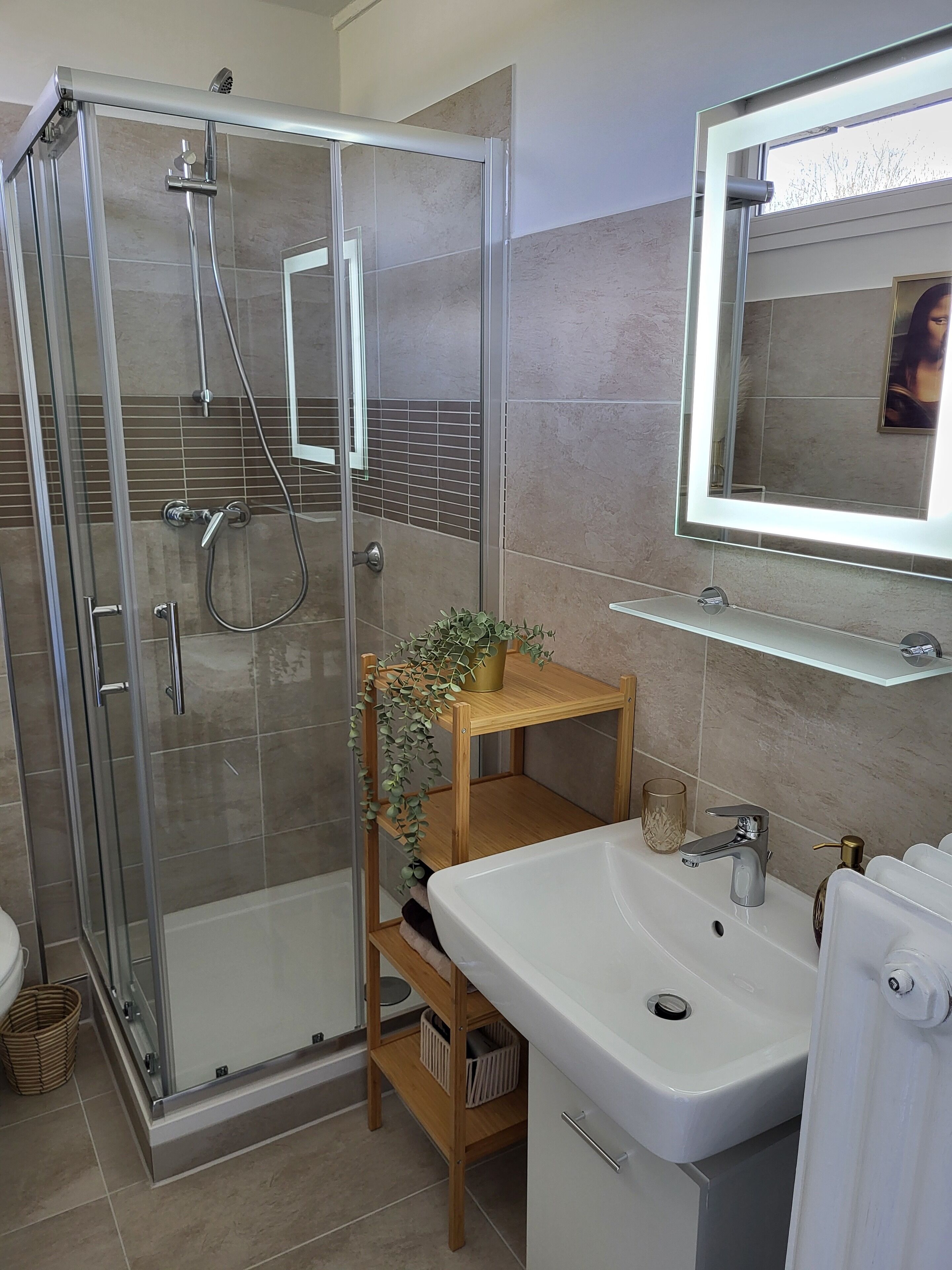 Un bany modern amb dutxa envidriada, un lavabo blanc i un mirall sobre el lavabo.