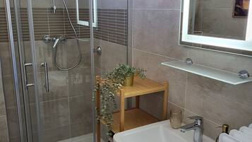 Un bany modern amb dutxa envidriada, un lavabo blanc i un mirall sobre el lavabo.