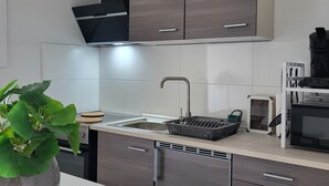Una cuina moderna amb armaris de fusta fosca, una aixeta d'acer inoxidable i una campana extractora negra.