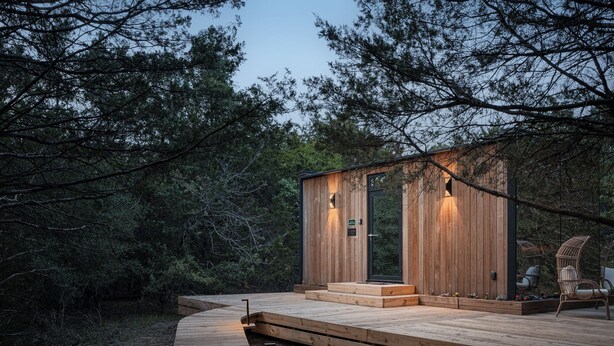 Una baita di legno con una veranda, circondata da alberi.