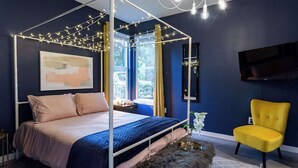 A bedroom with a four-poster bed, a yellow armchair, and a painting on the wall. - Modern ATX Mansion Walk to 6th Street (Austin)