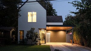 A modern two-story house with a garage, a well-maintained lawn, and a small garden area. - Modern ATX Mansion Walk to 6th Street (Austin)