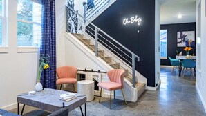 A modern interior with a staircase, a neon sign, and a dining area. - Modern ATX Mansion Walk to 6th Street (Austin)