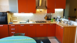 A compact kitchen with orange cabinets, a gas stove, and a sink.