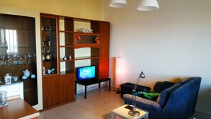 A living room with a TV, a wooden cabinet with shelves, a sofa, and a coffee table.