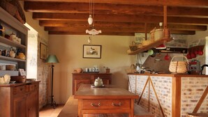 A rustic kitchen with wooden cabinets, a tiled floor, and a hanging light fixture. - MAS DE MAGAL GRAMAT (Gramat)