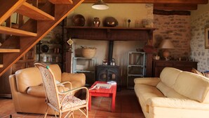 A cozy living room with a fireplace, leather sofas, a wicker chair, and a red coffee table. - MAS DE MAGAL GRAMAT (Gramat)