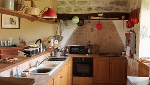 A compact kitchen with wooden cabinets, a built-in oven, a sink, and a tiled backsplash. - MAS DE MAGAL GRAMAT (Gramat)