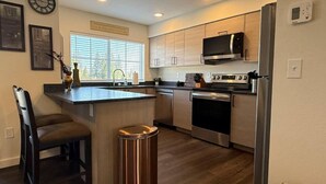 A modern kitchen with a central island, stainless steel appliances, and wooden cabinetry. - Homestead Village - Two Bedroom Condo Balcony (Sandpoint)