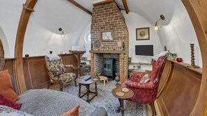 A cozy room with a brick fireplace, wooden beams, and a round table. - Retreat in Suffolk's Woodland Countryside (Bury St Edmunds)