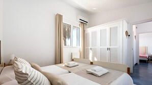 A bedroom with a large bed, two pillows, a bedside table with a lamp, and a window with curtains. - Villa Roxana, by the sea and with private pool (ES CASTELL)