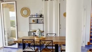 A dining area with a wooden table and chairs, a bookshelf, and a mirror on the wall. - Villa Roxana, by the sea and with private pool (ES CASTELL)