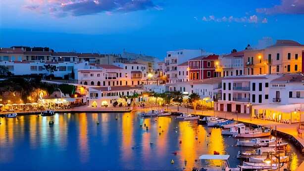 A coastal town at dusk with buildings along the waterfront, a marina with boats, and a clear sky. - Villa Roxana, by the sea and with private pool (ES CASTELL)