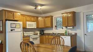 Una cocina con armarios de madera, un refrigerador, un microondas, una estufa y un lavamanos.