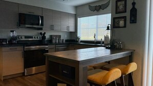 Une cuisine moderne dotée d’appareils électroménagers en acier inoxydable, de meubles en bois et d’un îlot central avec des tabourets de bar.