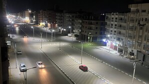 Une rue de la ville de nuit, avec des immeubles, des lampadaires et des véhicules.