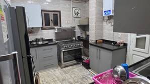 Une cuisine moderne dotée d’appareils électroménagers en acier inoxydable, de meubles gris et d’un tapis à motifs.