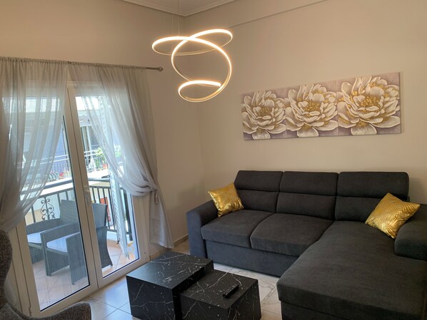 Ett modernt vardagsrum med en grå soffa, två guldfärgade kuddar, ett soffbord i marmor och ett stort, blommigt konstverk på väggen.
