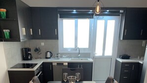 Una cucina moderna con mobili scuri, un tavolo da pranzo per quattro con piatti e bicchieri, e una macchina per il caffè.
