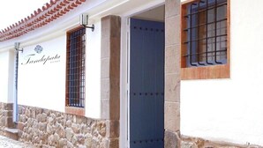 A building with a stone facade, a blue door, and barred windows. - Tandapata Boutique Hotel (Cusco)