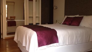 A bedroom with a large bed, a wardrobe, and a mirror. - Tandapata Boutique Hotel (Cusco)