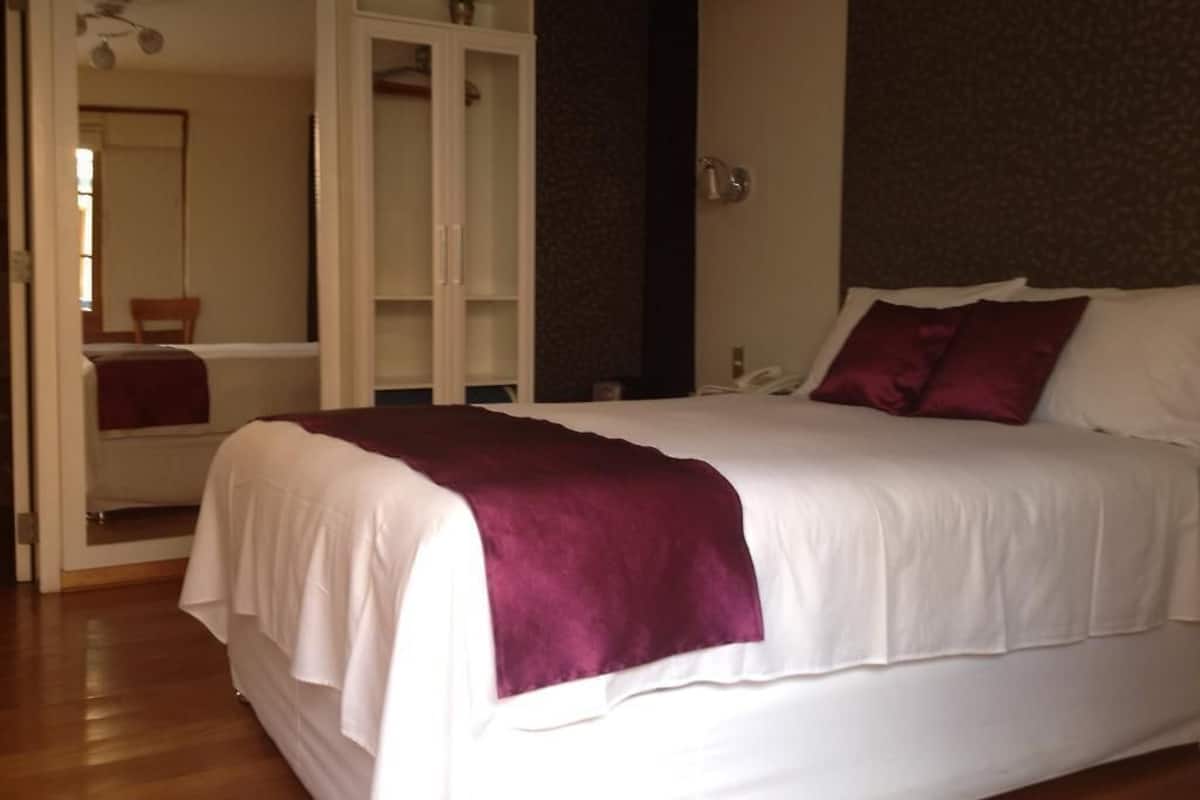 A bedroom with a large bed, a wardrobe, and a mirror.