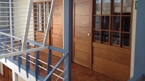A staircase with a metal railing, wooden doors with glass panels, and a tiled floor. - Tandapata Boutique Hotel (Cusco)