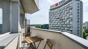 A balcony with a table and chairs, overlooking a high-rise building with the 'Pru' sign.