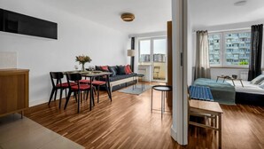 A modern apartment with a dining area, a sofa, a bed, and a view of buildings.